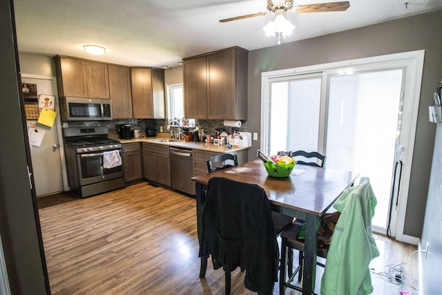7070 Quain Rd, Birch Run, MI 48415 - kitchen featuring stainless steel appliances, decorative backsplash, light wood finished floors, a sink, and ceiling fan