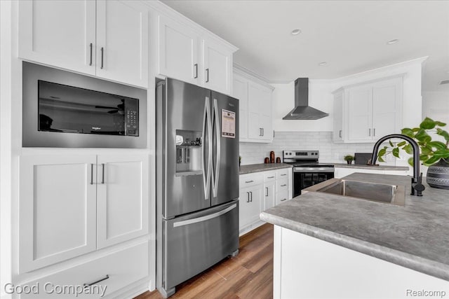 2826 16th St, Detroit, MI 48216 - kitchen featuring stainless steel appliances, wall chimney range hood, white cabinetry, wood finished floors, and decorative backsplash