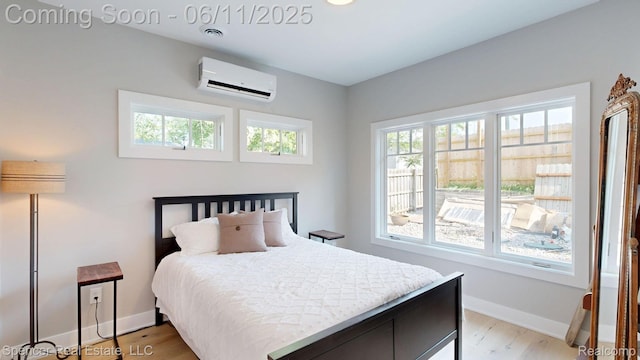 615 Dunleavy Dr, Highland, MI 48356 - bedroom featuring a wall mounted AC, light wood-style flooring, and baseboards