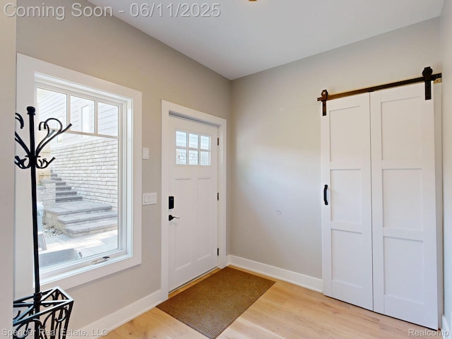 615 Dunleavy Dr, Highland, MI 48356 - entrance foyer featuring a barn door, light wood-style floors, and baseboards