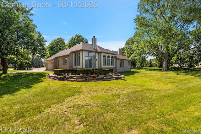 13815 Silent Woods Dr, Shelby Twp, MI 48315 - rear view of property featuring a chimney, a garage, a lawn, brick siding, and concrete driveway