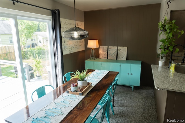 1247 Catalina Dr, Flint, MI 48507 - dining space featuring dark carpet and wood walls
