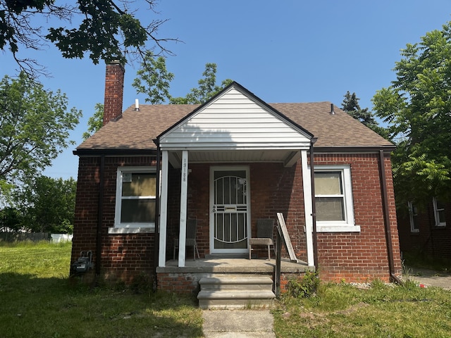 19188 Pelkey St, Detroit, MI 48205 - bungalow-style house featuring brick siding, a chimney, a shingled roof, and a porch