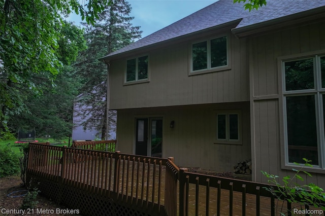 751 River Edge Ct, Flushing, MI 48433 - back of house featuring roof with shingles, a wooden deck, and a trampoline