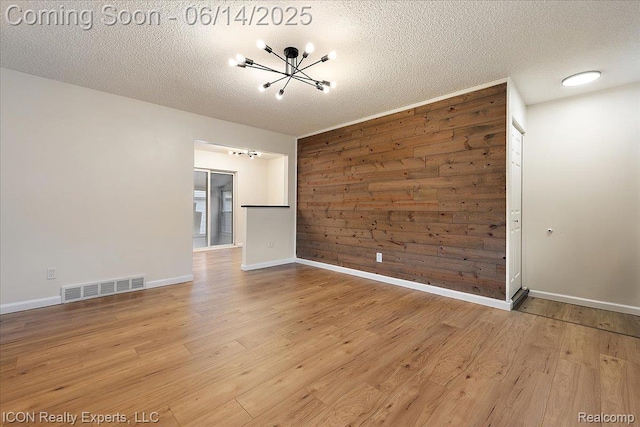 2570 Tarry Dr, Macomb, MI 48310 - unfurnished room with a chandelier, light wood-style floors, a textured ceiling, and baseboards