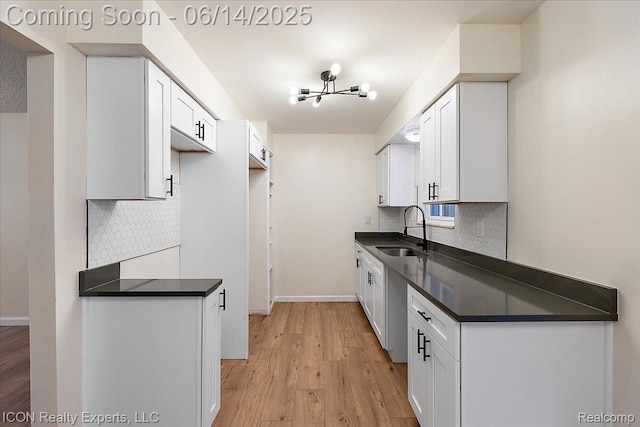 2570 Tarry Dr, Macomb, MI 48310 - kitchen featuring dark countertops, a sink, backsplash, and light wood-style flooring