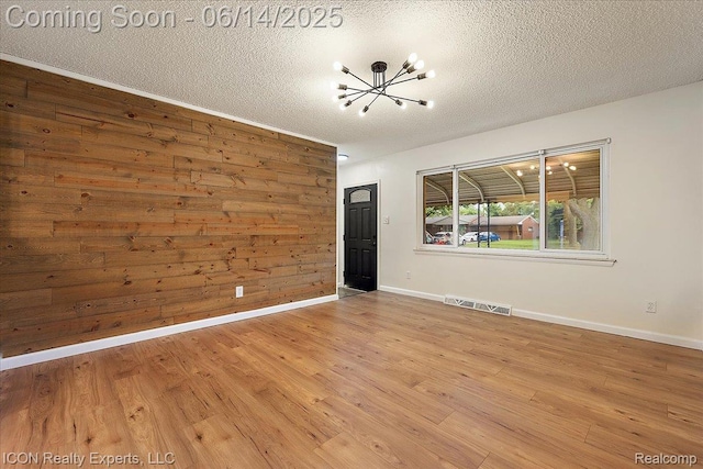 2570 Tarry Dr, Macomb, MI 48310 - unfurnished room featuring a chandelier, a textured ceiling, wood finished floors, baseboards, and wood walls
