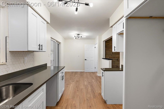 2570 Tarry Dr, Macomb, MI 48310 - kitchen with dark countertops, decorative backsplash, white cabinets, light wood-type flooring, and baseboards