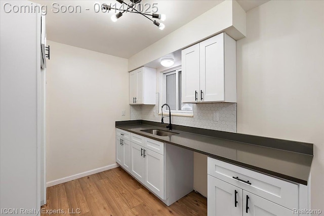 2570 Tarry Dr, Macomb, MI 48310 - kitchen with a sink, dark countertops, light wood-style floors, white cabinets, and a chandelier
