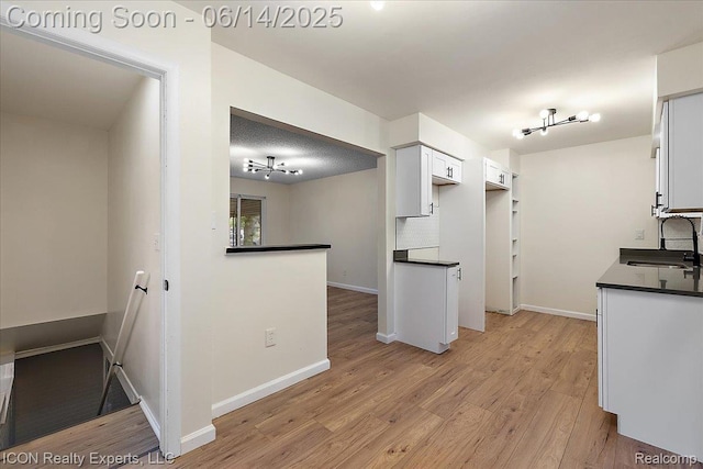 2570 Tarry Dr, Macomb, MI 48310 - kitchen featuring a sink, dark countertops, light wood finished floors, and white cabinets