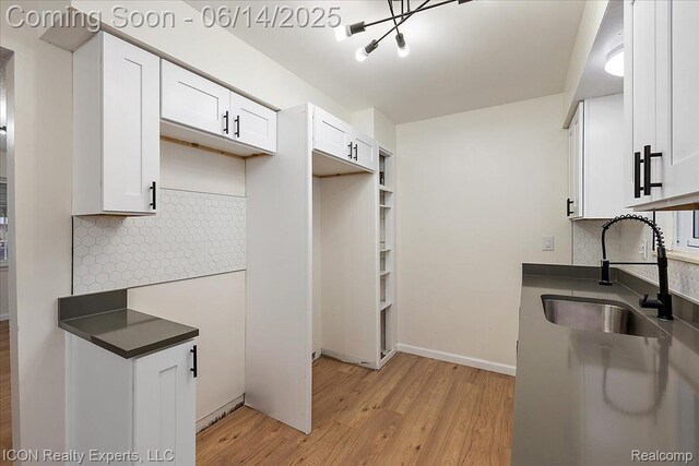2570 Tarry Dr, Macomb, MI 48310 - kitchen with a sink, light wood-style flooring, dark countertops, tasteful backsplash, and white cabinetry