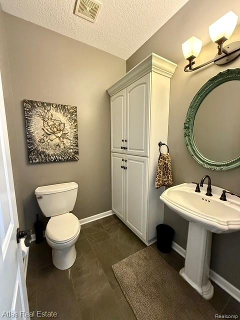 5415 Walker Rd, Davison, MI 48423 - half bathroom featuring toilet, a textured ceiling, and baseboards