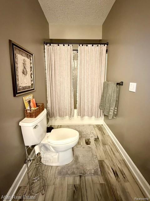 5415 Walker Rd, Davison, MI 48423 - bathroom with toilet, wood finished floors, a textured ceiling, and baseboards