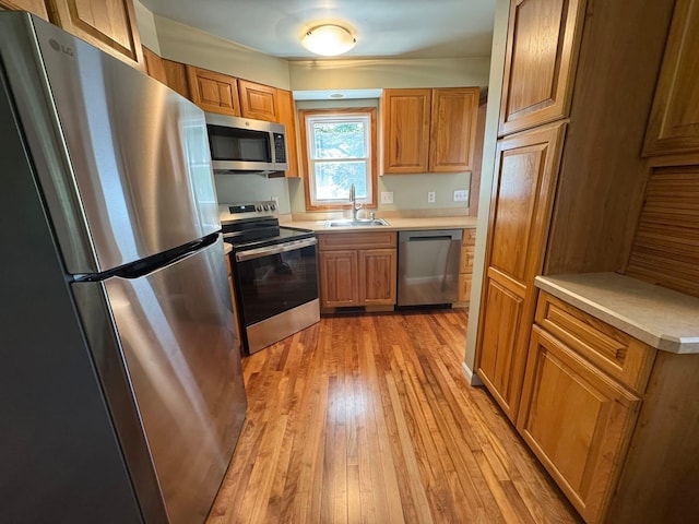 829 S Union St, Tecumseh, MI 49286 - kitchen with appliances with stainless steel finishes, a sink, light wood-style floors, light countertops, and brown cabinetry