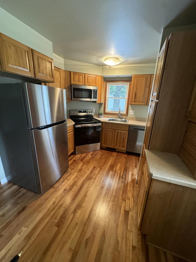 829 S Union St, Tecumseh, MI 49286 - kitchen with stainless steel appliances, a sink, light countertops, light wood-style flooring, and brown cabinetry