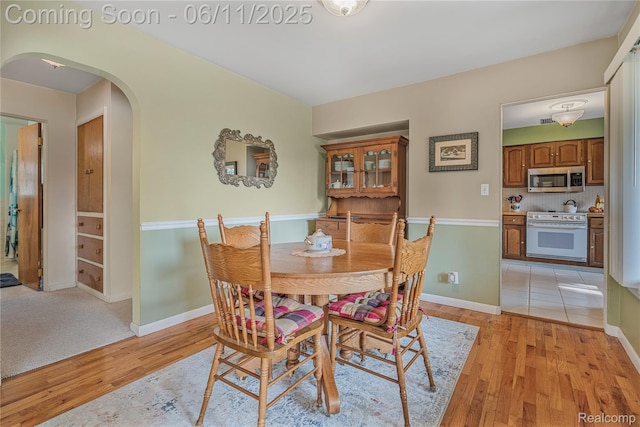 8351 Duffield Rd, Gaines, MI 48436 - dining room featuring arched walkways, light wood finished floors, and baseboards