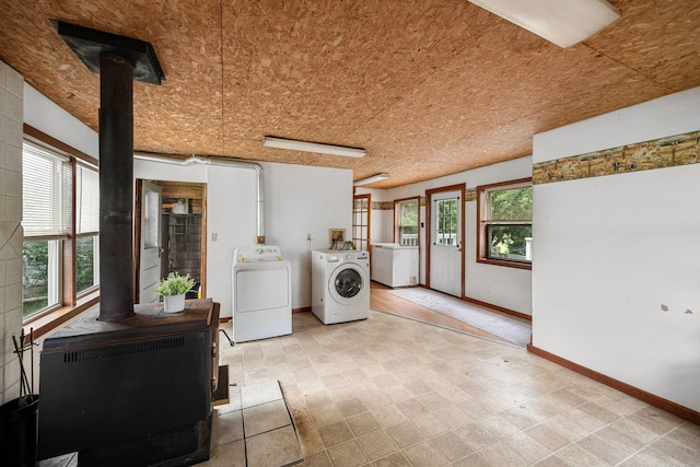 1820 E Rocky Weed Rd, Berrien Springs, MI 49103 - laundry room featuring a wood stove, washer and clothes dryer, baseboards, and healthy amount of natural light