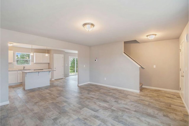 13678 Oasis Ave, Holland, MI 49424 - unfurnished living room with light wood-style flooring, baseboards, stairs, and a sink