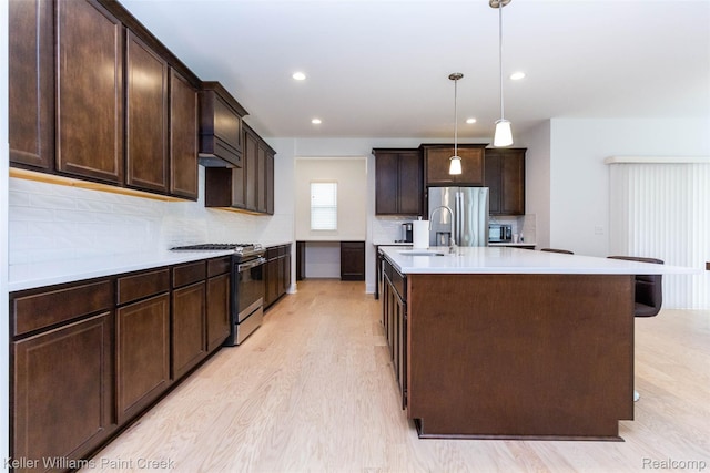 24738 Callaway Dr, Macomb, MI 48042 - kitchen featuring stainless steel appliances, dark brown cabinetry, decorative backsplash, light wood-type flooring, and light countertops