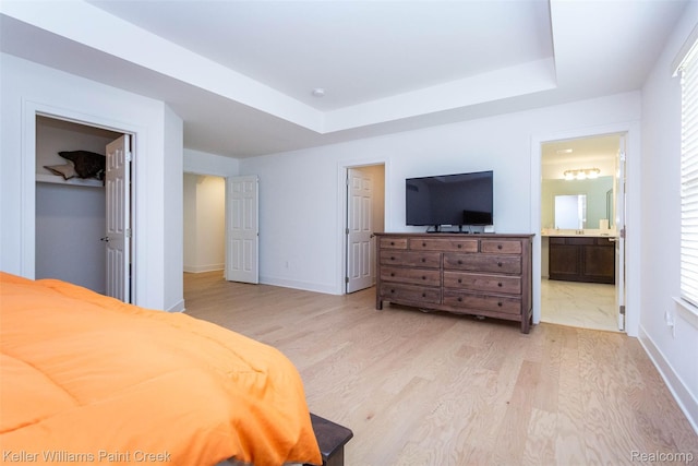 24738 Callaway Dr, Macomb, MI 48042 - bedroom featuring light wood-style floors, a raised ceiling, ensuite bathroom, and a walk in closet