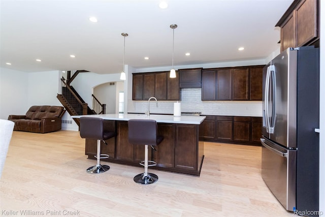 24738 Callaway Dr, Macomb, MI 48042 - kitchen with freestanding refrigerator, light countertops, light wood-style floors, decorative backsplash, and dark brown cabinets