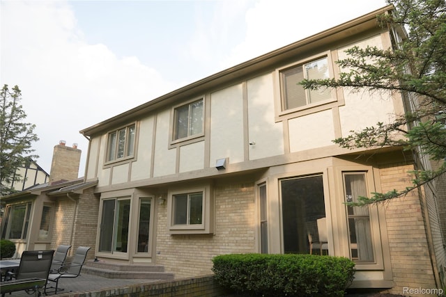 4567 Odette Ct, Troy, MI 48098 - rear view of property featuring stucco siding, brick siding, a chimney, and a patio area