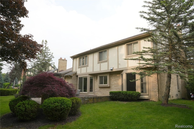 4567 Odette Ct, Troy, MI 48098 - rear view of house with brick siding, stucco siding, a yard, and a chimney