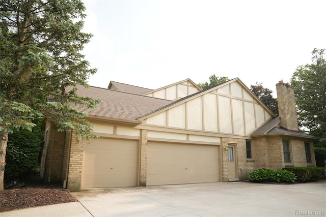 4567 Odette Ct, Troy, MI 48098 - tudor-style house featuring brick siding, a garage, concrete driveway, and roof with shingles