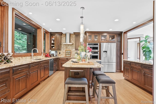 15349 Lakeside St, Plymouth, MI 48170 - kitchen featuring stainless steel appliances, wall chimney exhaust hood, a kitchen island, light wood finished floors, and decorative backsplash