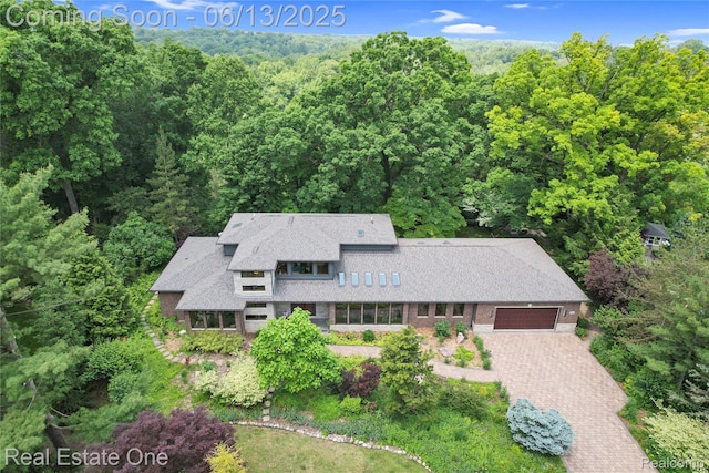 15349 Lakeside St, Plymouth, MI 48170 - view of front of house with a garage, a forest view, driveway, and brick siding