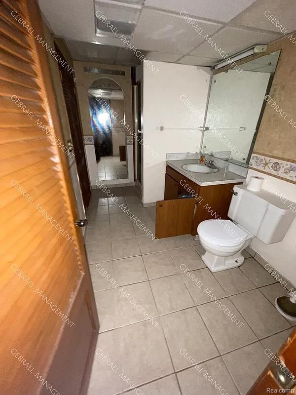 2307 Monteith St, Flint, MI 48504 - bathroom featuring tile patterned flooring, vanity, toilet, and a drop ceiling