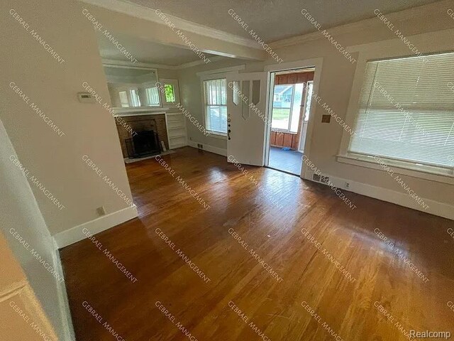 2307 Monteith St, Flint, MI 48504 - unfurnished living room featuring crown molding, a fireplace with flush hearth, baseboards, and wood finished floors