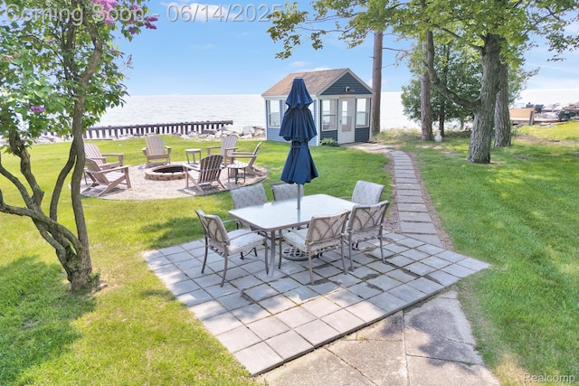 2968 Wolverine Rd, East Tawas, MI 48730 - view of patio with a fire pit, a water view, an outbuilding, and outdoor dining space