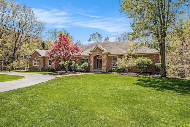6526 Ada Dr SE, Ada, MI 49301 - view of front of house with brick siding, a front yard, curved driveway, and roof with shingles