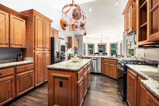 6526 Ada Dr SE, Ada, MI 49301 - kitchen featuring stainless steel appliances, brown cabinets, a sink, dark wood-type flooring, and light stone counters
