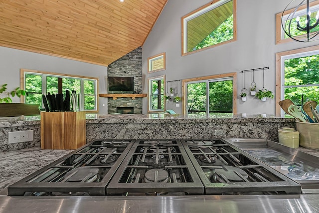 9725 Green Briar Rd, Lake Ann, MI 49650 - kitchen with high vaulted ceiling, black gas stovetop, a stone fireplace, and wood ceiling