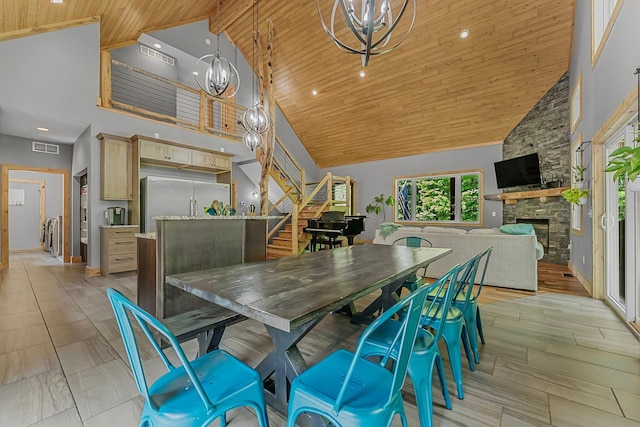 9725 Green Briar Rd, Lake Ann, MI 49650 - dining room with high vaulted ceiling, wood ceiling, stairs, a stone fireplace, and a chandelier