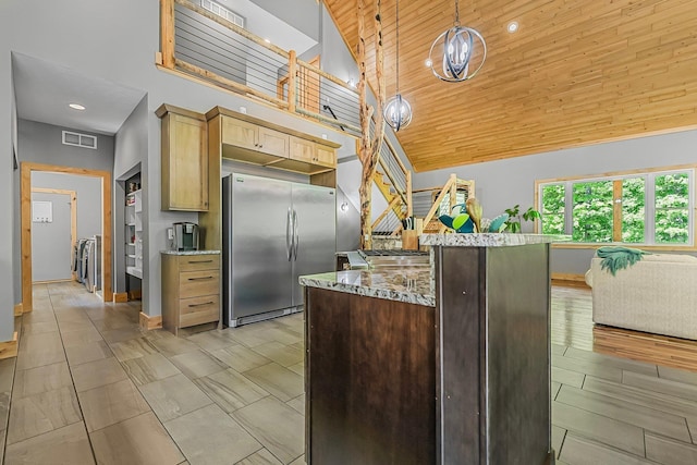 9725 Green Briar Rd, Lake Ann, MI 49650 - kitchen with freestanding refrigerator, a towering ceiling, light stone counters, open floor plan, and decorative light fixtures