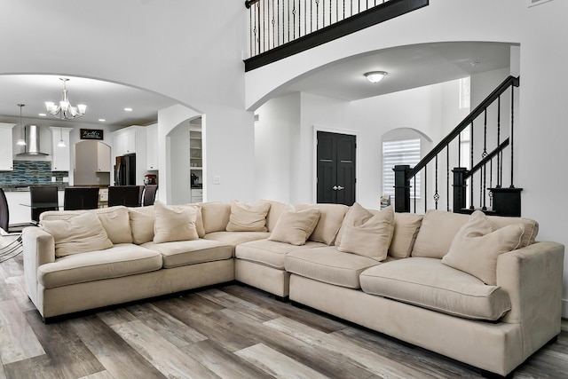 55135 Hanford Ct, Utica, MI 48316 - living room featuring a high ceiling, wood finished floors, arched walkways, a chandelier, and stairway