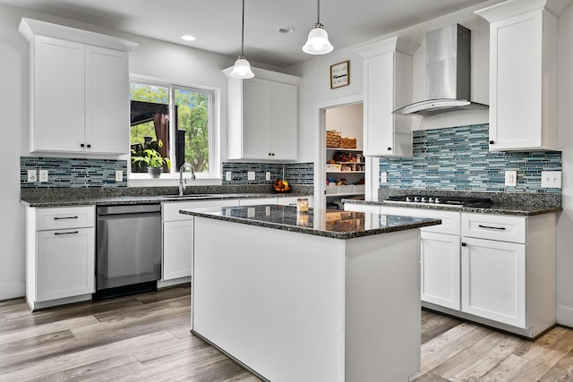 55135 Hanford Ct, Utica, MI 48316 - kitchen featuring wall chimney range hood, stainless steel dishwasher, gas stovetop, a kitchen island, and white cabinetry