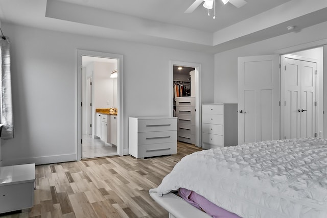 55135 Hanford Ct, Utica, MI 48316 - bedroom featuring light wood-style floors, ensuite bathroom, a closet, and a tray ceiling
