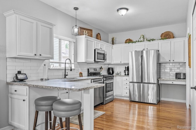 1156 Fairway Dr, Pontiac, MI 48340 - kitchen with stainless steel appliances, a peninsula, white cabinets, a breakfast bar, and decorative backsplash