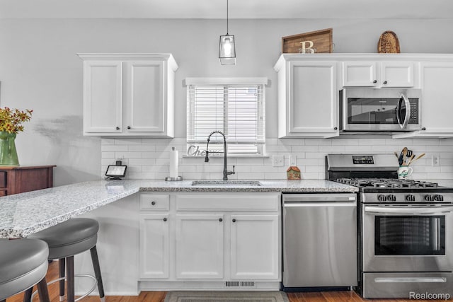 1156 Fairway Dr, Pontiac, MI 48340 - kitchen with appliances with stainless steel finishes, white cabinets, light stone counters, and tasteful backsplash