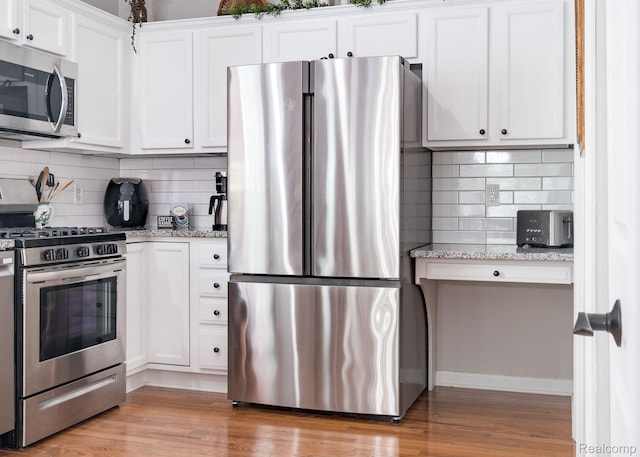 1156 Fairway Dr, Pontiac, MI 48340 - kitchen featuring appliances with stainless steel finishes, decorative backsplash, white cabinets, light wood-style flooring, and light stone countertops