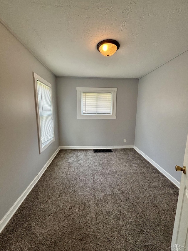 2138 N Clinton St, Saginaw, MI 48602 - empty room with a textured ceiling, dark carpet, and baseboards
