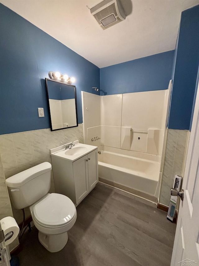 2138 N Clinton St, Saginaw, MI 48602 - bathroom featuring tile walls, toilet, vanity, shower / washtub combination, and wood finished floors
