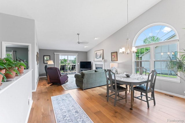 11118 Strathmore Ct, Grand Blanc, MI 48439 - dining room with light wood-style flooring, a chandelier, a tile fireplace, baseboards, and high vaulted ceiling