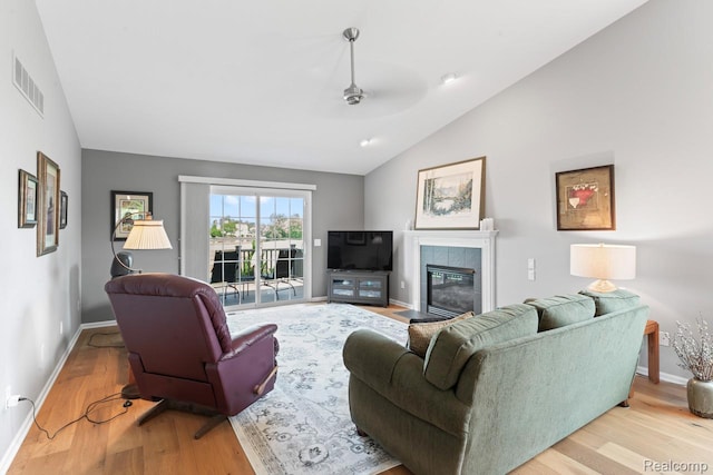 11118 Strathmore Ct, Grand Blanc, MI 48439 - living room with vaulted ceiling, wood finished floors, ceiling fan, baseboards, and a tiled fireplace