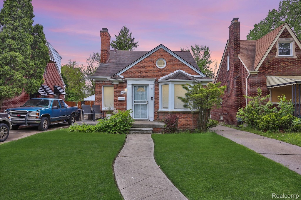 9666 E Outer Dr, Detroit, MI 48213 - view of front of property featuring a front yard, a chimney, brick siding, and a shingled roof