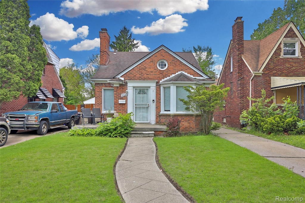 9666 E Outer Dr, Detroit, MI 48213 - view of front facade with brick siding, a chimney, a front lawn, and a shingled roof